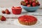 Chocolate tart, tartalette with white chocolate and mascarpone cream, fresh strawberries on top. Large blue bowl full of