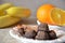 Chocolate truffles of candy on a plate, with cinnamon and anise. On a serviced table with bananas and oranges