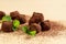 Chocolate truffles and fresh mint over beige background. Dark chocolate candies sprinkled with cocoa powder closeup. Gourmet