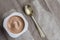 Chocolate yogurt pot wit small silver spoon, isolated on brown table cloth