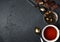 Chocolates and black tea with herbs. Metal tea strainer, spoon. Dark background. Copy space. Flat lay