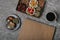 Chocolates with dried fruits in a box and craft paper notebook near the cup of coffee