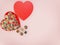 Chocolates sweets in a red heart shaped box with copyspace for text over a pink flatlay background