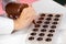 Chocolatier pouring caramel filling into chocolate mold preparing handmade candy