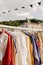 Choice of fashion clothes of different colors on hangers in a retail shop. Flea market with old clothes outside. Reduce Reuse