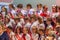 Choir of pupils standing on the stage. Festive students holding flowers.