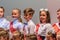 Choir of pupils standing on the stage. Festive students holding flowers.