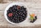 Chokeberry in bowl and berries cluster on old wooden surface