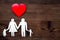 Choose family health insurance. Paper heart and silhouette of family on dark wooden background top view copyspace