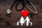 Choose family health insurance. Stethoscope, paper heart and silhouette of family on dark wooden background top view