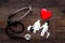 Choose family health insurance. Stethoscope, paper heart and silhouette of family on dark wooden background top view