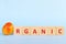 Choose organic food concept. Wooden blocks and tomato with word organic in blue background with copy space.