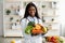 Choose quality healthy food. Happy black nutritionist holding bowl of fresh fruits and vegetables, smiling at camera