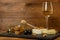 Chopped camembert cheese, nuts, honey, sweet grapes and cork from wine bottle on the background of a glass of white dry wine
