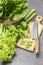 Chopped celery stalks, kitchen knife on cutting board. Lettuce leaves in wicker basket