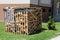 Chopped firewood stacked in leaning wooden frames and prepared for cold winter days in front of newly renovated apartment building