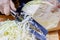 Chopped fresh juicy white cabbage. Woman hand shredding cabbage on the wooden cutting board by stainless steel knife