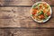 Chopped frozen vegetables in a plate on a wooden background. Corn peas pepper carrots. copy space