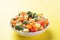 Chopped frozen vegetables in a plate on a yellow background. Corn peas pepper carrots. copy space