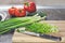 Chopped green onions and vegetables on striped wooden board