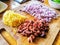 Chopped olives and onion and grated cheese on a bamboo chopping board