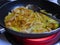 Chopped onions frying in a frying pan on a the stove with a bit of oil and some spices.