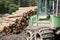 Chopped stacked wood logs for fuel and tractor digger in forest