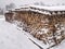 Chopped stock of firewood under snow, regular pile from wood