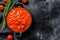 Chopped tinned red tomatoes in a pan. Black background. Top view. Copy space