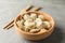 Chopsticks and bowl with dumplings on grey background