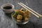 Chopsticks on a bowl of fried tofu cheese on a wooden table.