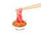 A chopsticks holding sliced beef dipping sauce on white background