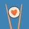 Chopsticks holding sushi roll, heart shape salmon roll, concept of snack, susi, sushi restaurant, sea food