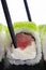Chopsticks taking sushi rolls with tuna and caviar