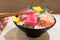 Chopsticks with Tuna sashimi with Mixed sliced fish sashimi on ice in black bowl. Sashimi Salmon Tuna Hamachi Prawn and Surf Calm