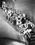 A chorus line standing on a curved stair case