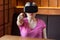 Chose you! Portrait of young woman in pink t-shirt sitting in cafe, wearing virtual reality headset and watching video, playing