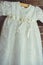 Christening baby dress. Close-up of a cute newborn baby dress. Stylish embroidered white dress. Concept childhood education and fa