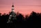 Christian church with evening lighting with trees silhouettes on the beautiful pink sunset