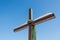 Christian cross with green wreath and ribbons on the plain blue sky background, Concept of hope, faith, love