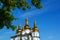 Christian Cross which is visible through the tree leaves. White church, orthodox, Russia, blue sky, view