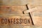 Christian cross and word Confession on wooden background, top view