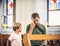 Christian dad tells his son Bible stories about Jesus sitting in kirk. Faith, religious education, modern church, father