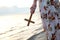 Christian lady girl holding a holy cross in her hand and standing on the beach during sunset evening time.