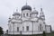 Christian orthodox white church with silver and grey domes with gold crosses. Calm grey sky above