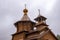 Christian orthodox wooden church with gold domes and crosses. Calm grey sky above
