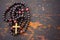 Christian rosary prayer with a cross on old black wooden background