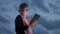 A Christian woman reads a bible at dusk against the background of thunderclouds