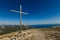 Christian wooden cross on mountain top, rocky summit, beautiful inspirational landscape with ocean, clouds and blue sky
