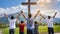 Christian worshipers raising hands up in the air in front of the cross